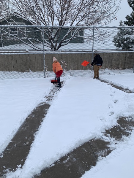 Two students shoveling snow to clear a path.