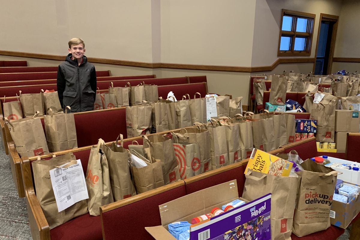 Brandon in a church sanctuary with dozens of paper-bag Thanksgiving meals arranged on the pews