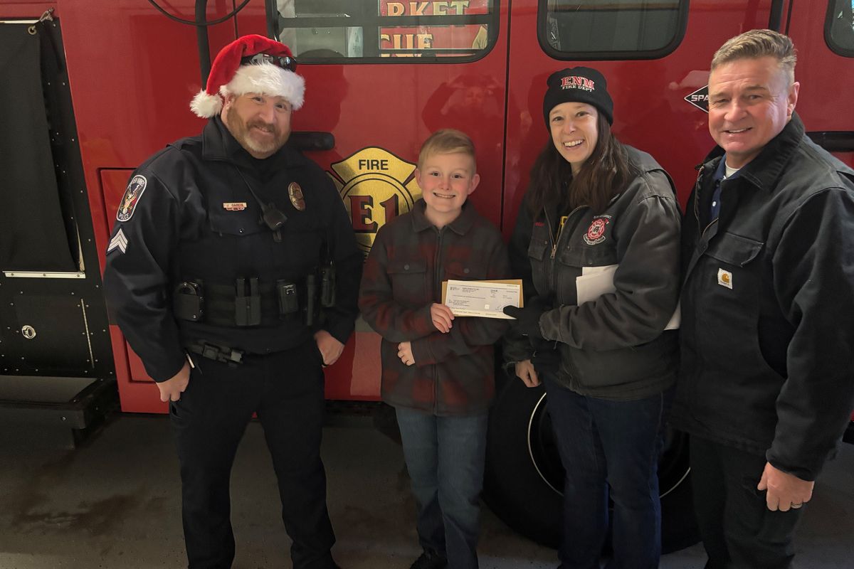 Declan presents a check to the Hope for the Community food shelf team at a local fire station