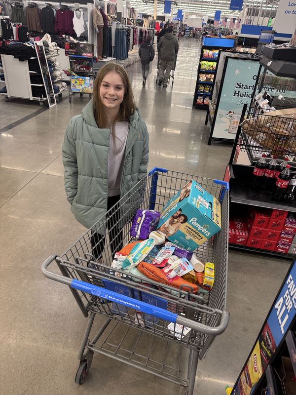 A student with a cart of diapers and baby supplies for Kaitlyn's Kloset and Adopt-a-Family